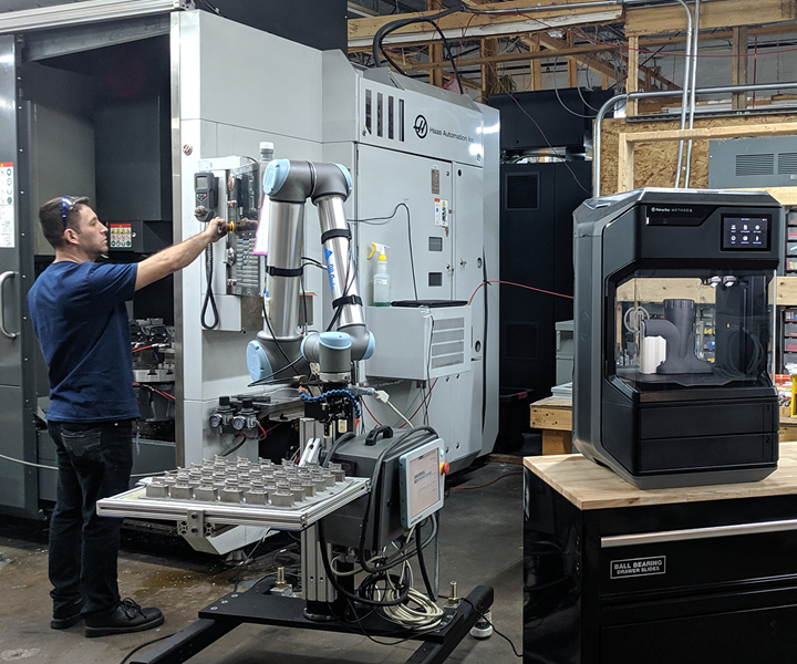 Man at machine with cobot near a desktop 3D printer